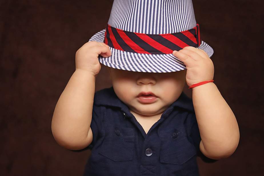 Little baby boy in a hat with the red robe on the hand