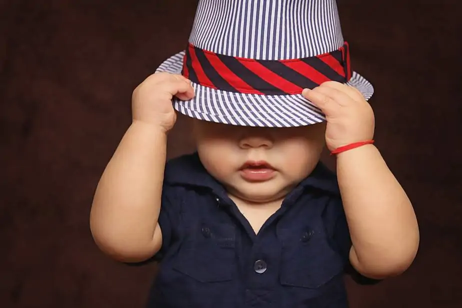 Little baby boy in a hat with the red robe on the hand